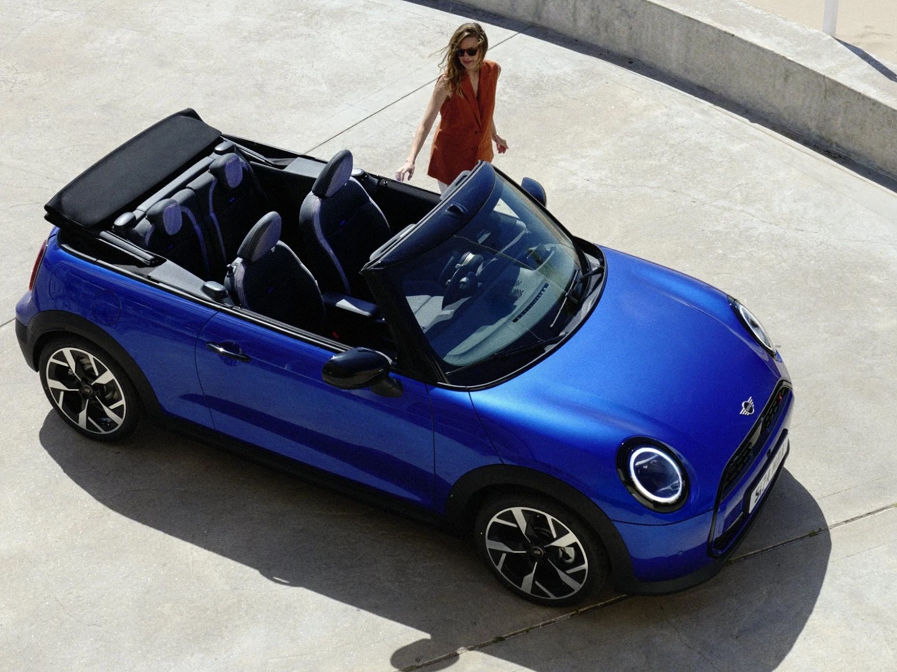 Seitenansicht eines MINI Cooper Cabrio in Chili Red auf einer Straße.